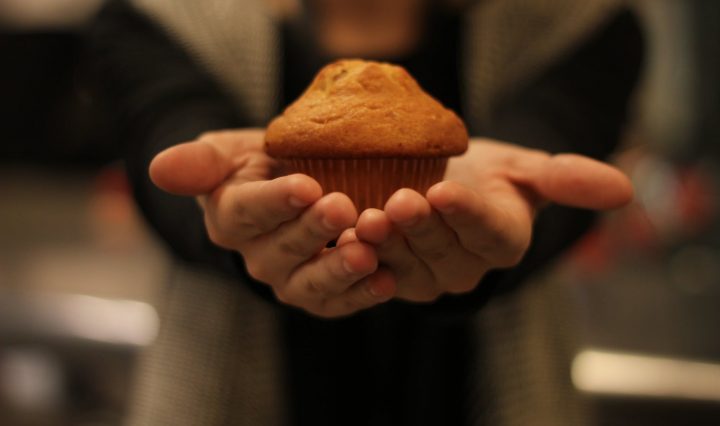 person s hand with cupcake